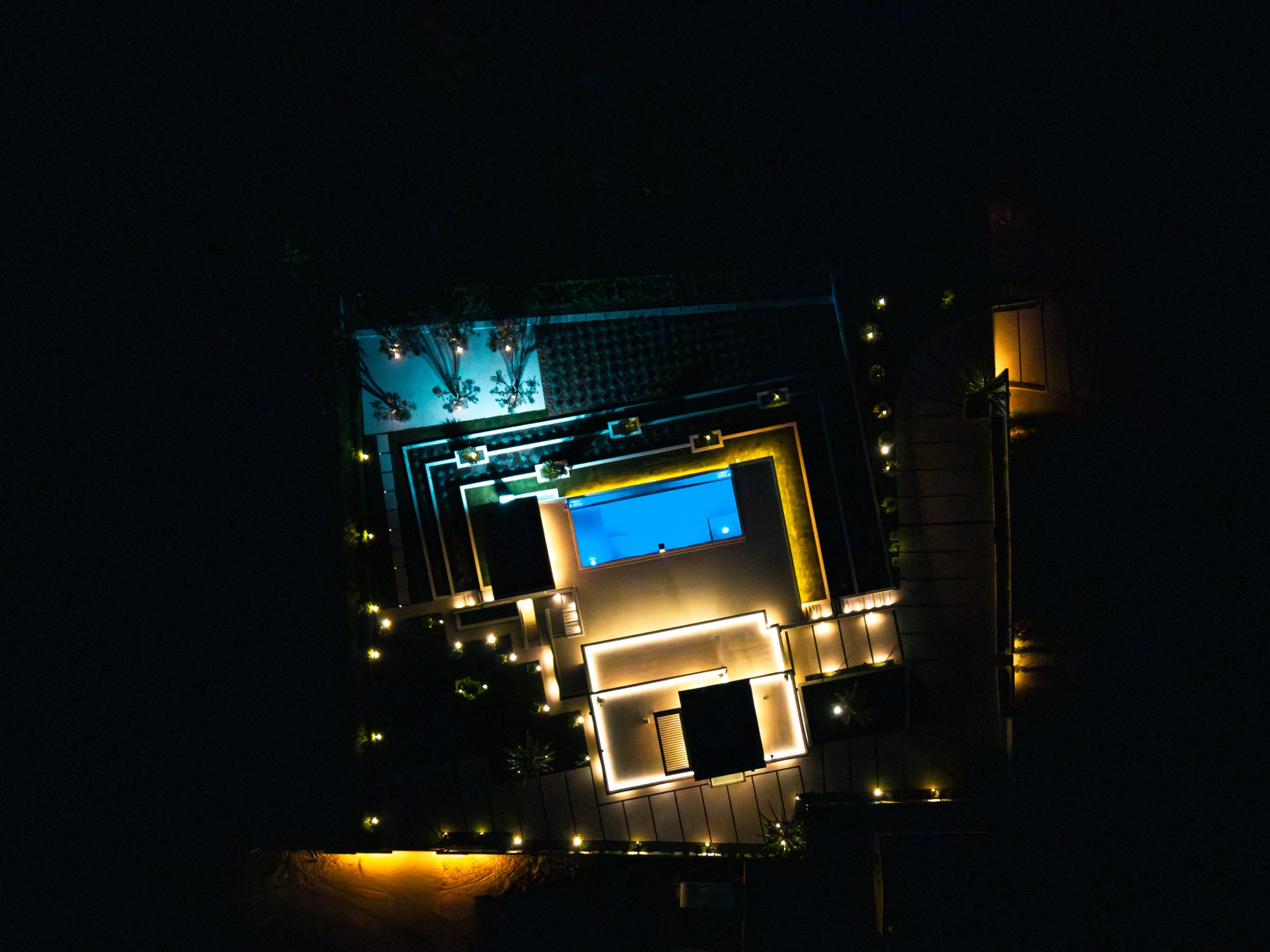The lit villa and pool at night, from above